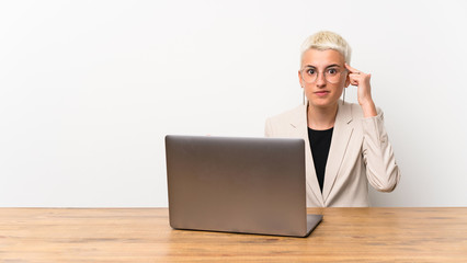 Teenager girl with short hair with a laptop making the gesture of madness putting finger on the head