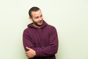 Fototapeta premium Colombian man with sweatshirt over green wall thinking an idea