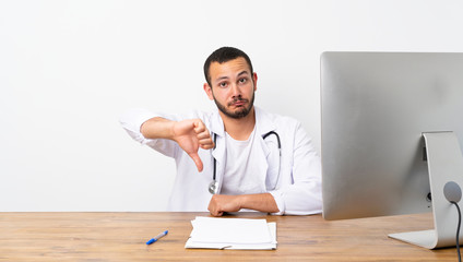 Doctor Colombian man showing thumb down with negative expression