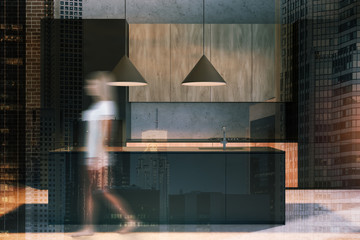 Woman walking in concrete kitchen with island