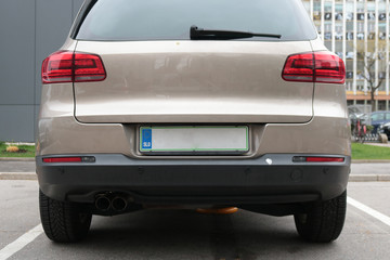 Empty license plate on the back of a beige car 