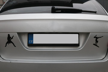 Empty License plate on the back of a grey silver car with stickers