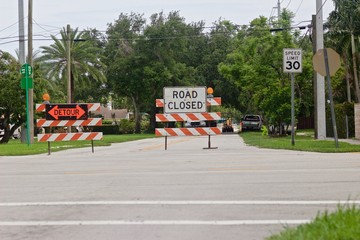 Detour sign and Road Closed signs on orange and white striped road barricades with flashing light