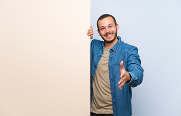 Colombian man holding an empty placard handshaking after good deal