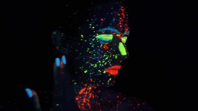 paint glowing in ultraviolet light. portrait of a girl painted with glowing paint.