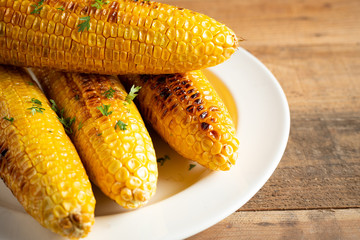 Grilled corn cobs on wood background.