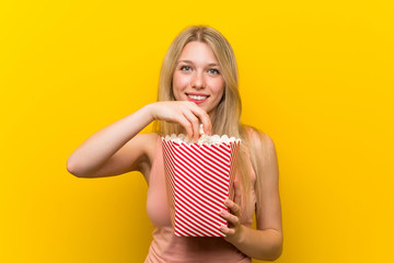 Young woman with popcorns over pink wall