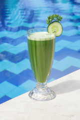 Fresh organic green smoothie in the glass next to the pool, healthy summer day refreshment