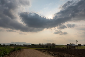 Fototapeta na wymiar landscape of country road pass through the farm with dramatic cloud sky of the evening, Mae Ramat, Tak, Thailand