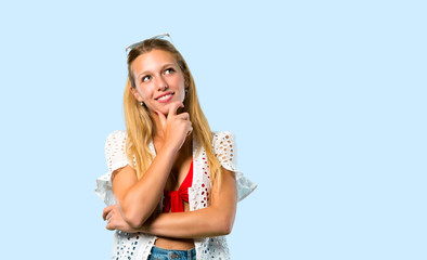 Blonde girl in summer vacation thinking an idea on blue background