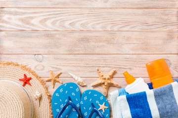 flip flops, straw hat, starfish, sunscreen bottle, body lotion spray on wooden background top view . flat lay summer beach sea accessories background, vaation concept