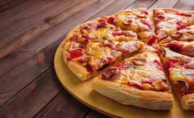 sliced homemade pizza with sausage cheese  on wooden background copy space
