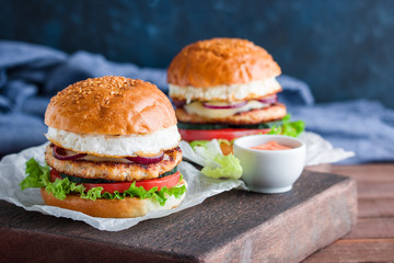 chicken burgers with fried egg cucumber tomato mozzarella cheese lettuce on cutting board