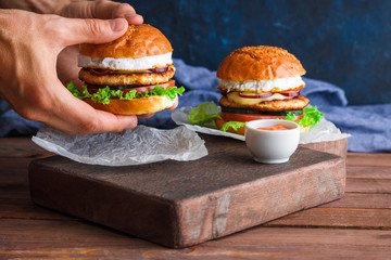 man hands holding chicken burger with fried egg cutlet lettuce red onion tomato