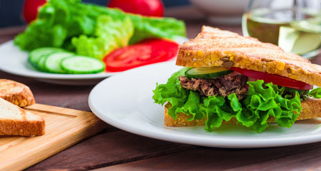 homemade sandwich with tuna  grilled bread  lettuce tomato cucumber on white plate close up