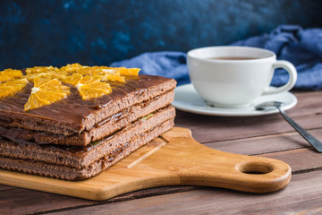 homemade chocolate sponge cake with orange slices on cutting board cup of tea
