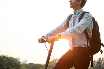 Young office worker with backpack behind his back using scooter as a means of transportation on the street, he coming back from work © DragonImages