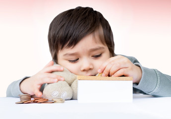 Selective focus of a little boy putting pound coin on a moneybox, Blurry face of cute boy counting his saved coins and thinking about somethings,Child learning about saving concept