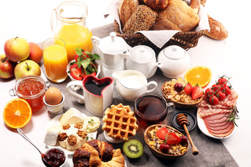 Huge healthy breakfast on table with coffee, orange juice, fruits, waffles and croissants. Good morning concept.