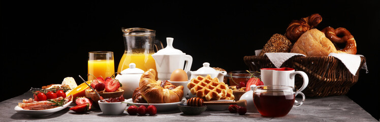 Huge healthy breakfast on table with coffee, orange juice, fruits, waffles and croissants. Good morning concept.