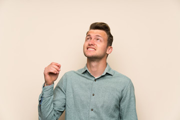 Blonde handsome man over isolated wall standing and thinking an idea