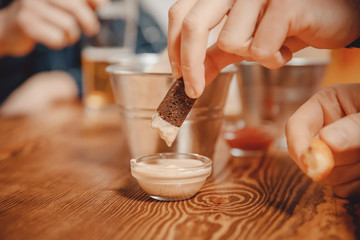 Beer and snacks crackers, croutons with sauce. Men in pub bar behind wooden table