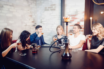 Obraz na płótnie Canvas Group of friends man women met in cafe, smoking shisha hookah, drinking tea, chatting