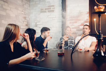Group of friends man women met in cafe, smoking shisha hookah, drinking tea, chatting