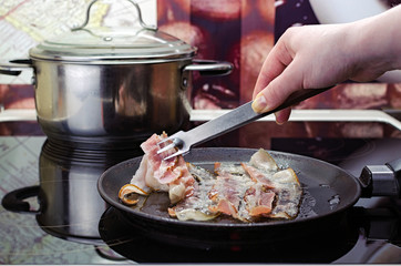 fry the bacon in the frying pan, the girl's hand puts bacon in the frying pan, cooking in the kitchen on the ceramic stove