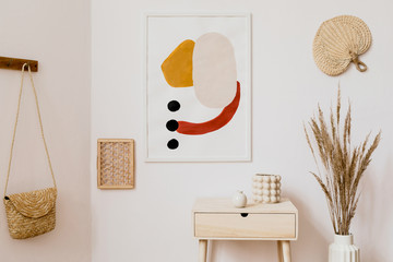 Stylish white interior of living room with mock up poster frame, rattan accessories, leaf, wooden shelf, vase with flowers and elegant personal stuff. Minimalistic concept of home decor. Template. 