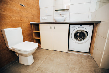 modern light interior. bathroom with round sink. ceramic tiles with wood texture. washing machine with a round drum.