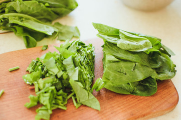 Crushed green sorrel, knife and bowls on the background of wooden boards