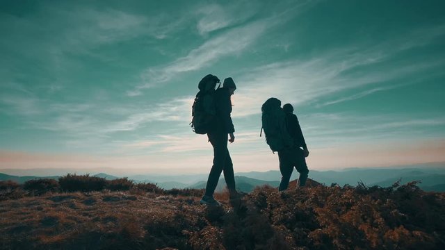 The hikers walking to the mountain on the sunset background. slow motion