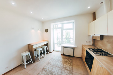 Fototapeta premium modern light interior. modern kitchen with steel hob. blue glass dining table and chairs. kitchen cabinets with wooden doors.