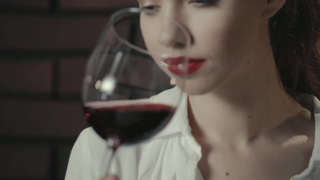 Attractive woman holding in hand wine glass. Pretty girl drinking red wine