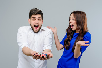 Attractive couple won a lot in online casino with poker chips isolated over grey background