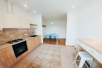 modern light interior. modern kitchen with steel hob. blue glass dining table and chairs. kitchen cabinets with wooden doors.