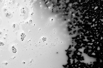 Spilled milk puddle with droplets isolated on black background and texture, top view