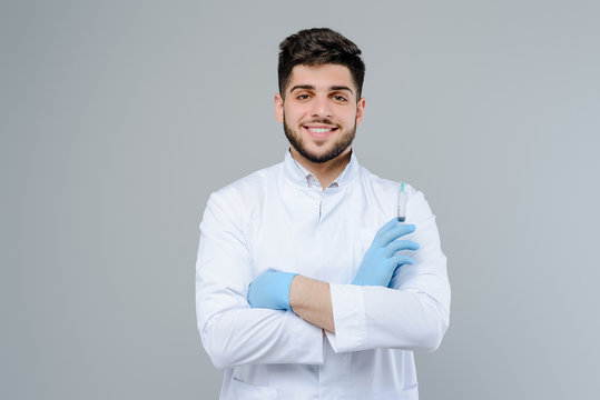 Smiling medical doctor in gloves with suringe isolated over grey background