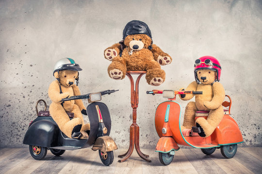 Teddy Bear retro toys in helmets with goggles sitting on old children's pedal scooters and Teddy Bear referee with whistle and leather hat. Competition concept. Vintage style filtered photo