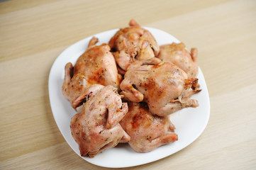 Six baked cornish hens on white plate top view