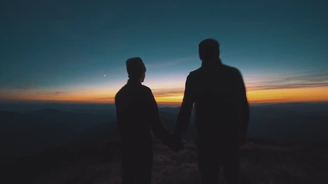 The couple standing in the mountain on the sunset background