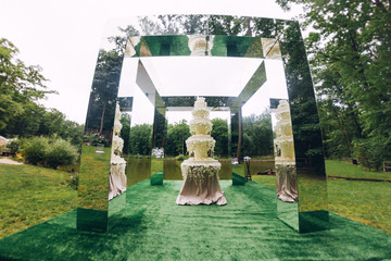luxury wedding cake. Marzipan flowers. layered dessert. Wedding mirror arch in the park.