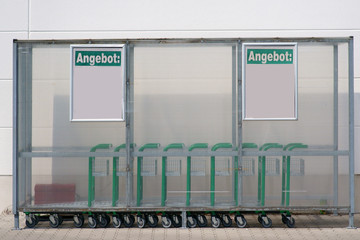 Ein Kunststoffunterstand mit Rollwagen außen vor dem Eingang eines Getränkehändlers. .