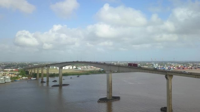 Wide angle aerial shot of Jules Wijdenbosch Bridge between Paramaribo and Meerzorg in Suriname, South America, with heavy traffic as drone gains in altitude to reveal a panoramic view.