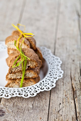 Fresh homemade Italian cookies cantuccini stacked on white plate on ructic wooden table background.