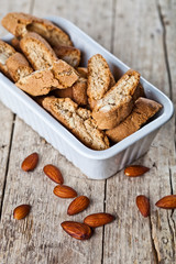Cookies cantuccini with almond seeds  in white ceramic bowl closeup on ructic wooden table background.