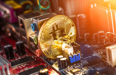 Golden Bitcoin Cryptocurrency on computer circuit board. Macro shot