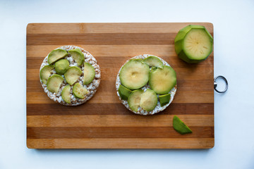 vegan rice bread with avocado on the wooden desk isolated on the white background. Vegan breakfast rice tortillas with avocado. Rice cakes with sliced avocado. Vegetarian, vegan concept..