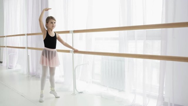 Little Ballerina in training in black and pink dancing suit.